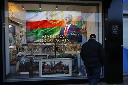 A man walks past a shop displaying the Iranian flag and an image of Reza Pahlavi