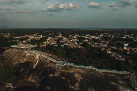 An elevated walkway winds down a rocky hill towards the town of Mucajaí, Brazil