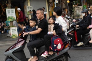 A man and two children on a motorbike with a schoolbag