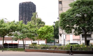 A boy looks towards the remains of Grenfell Tower.