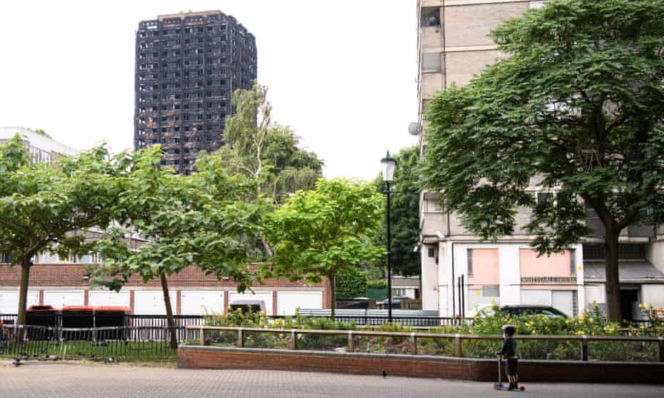 A boy looks towards the remains of Grenfell Tower.