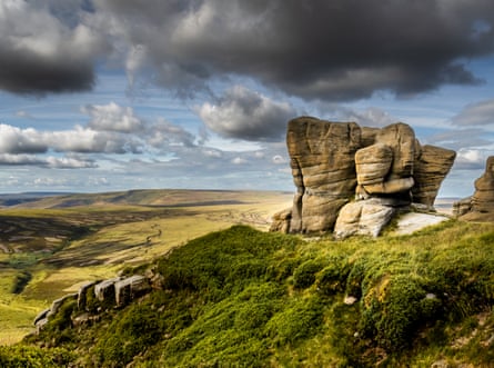A large configuration of white rocks on a green hill against a cloudy sky