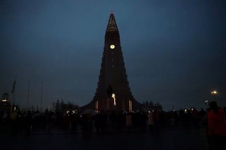 People gather to observe the total solar eclipse, as clouds cover the sky, in Reykjavik