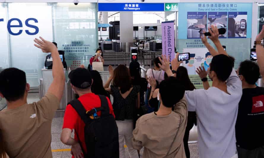 A woman takes photos of her friends waving goodbye before she boards a flight to Britain from Hong Kong airport