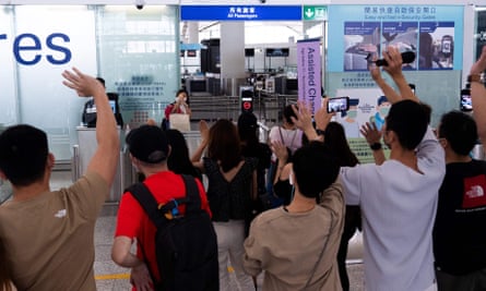 A woman takes photos of her friends before entering the departures hall for her flight to Britain