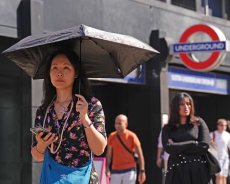 A woman uses an umbrella for shade near Euston Station in central London.
