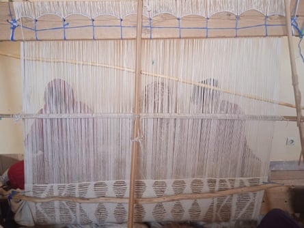 Three people seen behind a loom