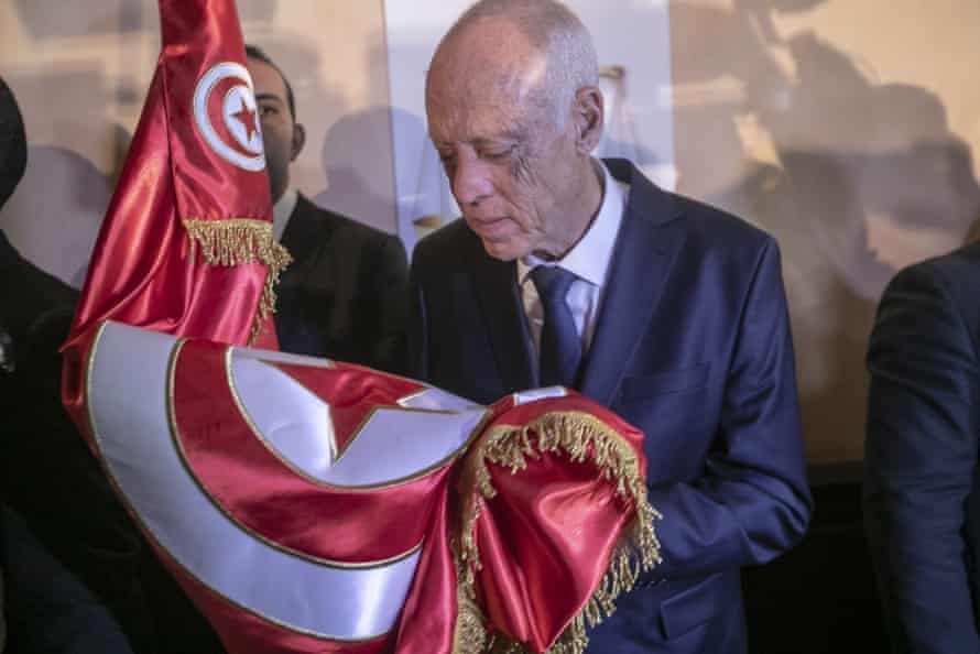 Independent candidate Kais Saied holds the Tunisian flag at a press conference after exit polls pointed to victory.