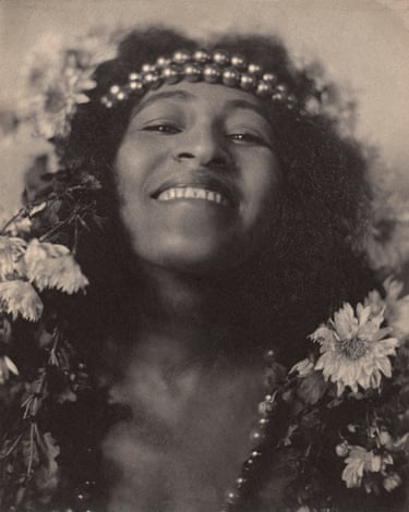 Lizzie Avery smiles, wearing a beaded headband and surrounded by flowers
