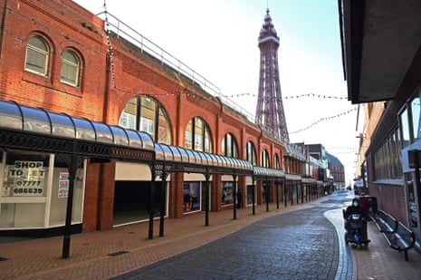 A pedestrian walks along an almost deserted shopping street, near the Blackpool Tower, in Blackpool, northwest England, on 25 January, 2021.