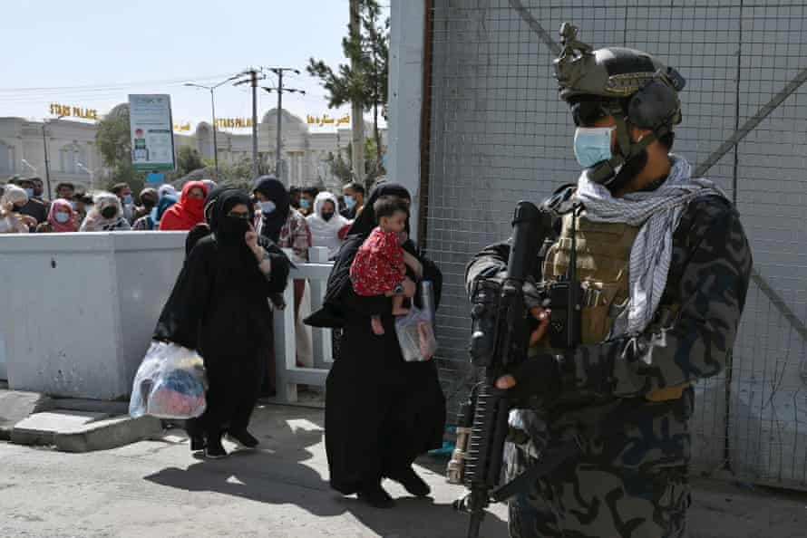 A member of Taliban Badri fighters, a ‘special forces’ unit, stands guard as Afghan walk thorough the main entrance gate of Kabul airport to leave Afghanistan in Kabul on Saturday.