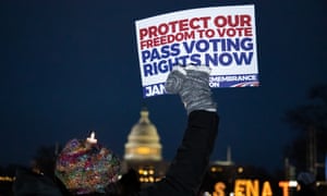 A person holds a sign at a candlelight vigil and rally for voting rights on the National Mall near the US Capitol building on 6 January 2022.