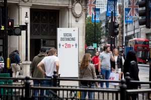 Shops on Oxford Street in central London near oxford Circus tube with signs requesting shoppers keep a 2m social distance from each other.