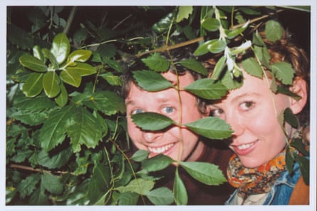 The couple peer out from behind foliage