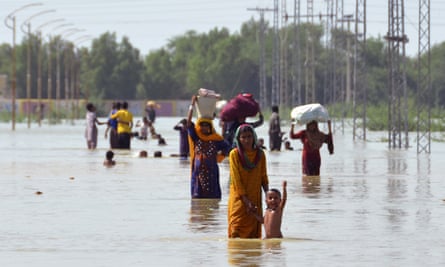 displaced people carry belongings along a flooded road in jaffarabad, south-eastern pakistan, in august this year