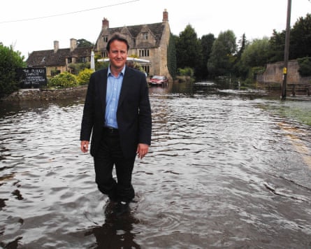 David Cameron standing in village flood water in front of stone houses