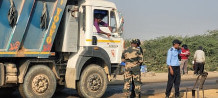 Guards stand next to a stationary lorry on a road