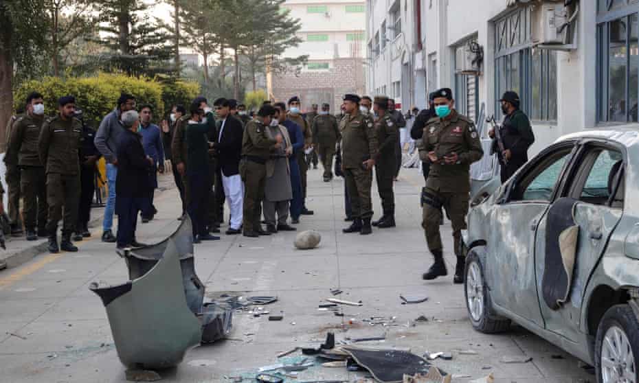 Security officials gather beside a damaged vehicle near the premises of a factory in Sialkot