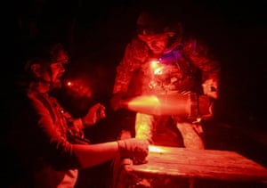 Two soldiers handle missile shells in the dark