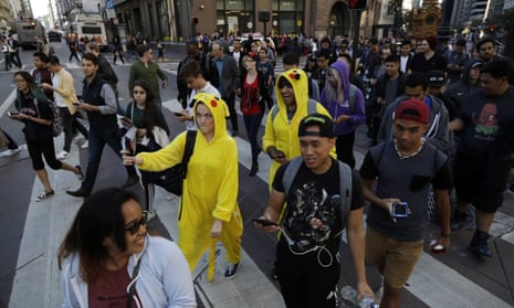 Pokémon Go players walk along Market Street on Wednesday on San Francisco.
