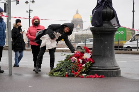 People lay flowers near the side of an explosion at the “Street Bar” cafe with the St. Isaac’s Cathedral in the background in St. Petersburg, Russia.
