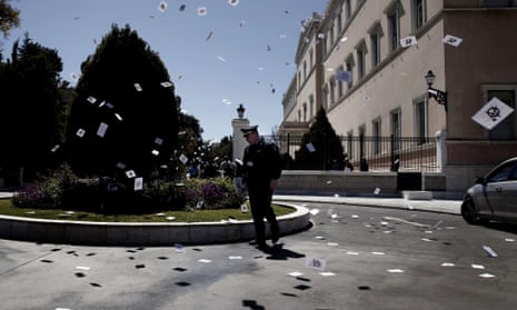 A police looks at leaflets fallin got the ground after they were thrown by anti-establishment protesters on April 1, 2015 outside the Greek Parliament in Athens in solidarity with hunger-striking inmates. The protesters managed to enter the parliament to show their solidarity with the political prisoners on a hunger strike since March 2. Banner reads: “Solidarity with hunger strikers-immediate satisfaction of their demands”. AFP PHOTO / KOSTIS NTANTAMISKOSTIS NTANTAMIS/AFP/Getty Images