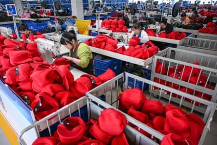 Employees work in a factory with metal baskets of red caps