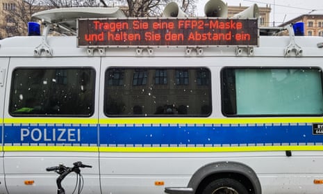 A sign above a Munich police van instructs people to wear an FFP2 mask and to maintain distancing. 
