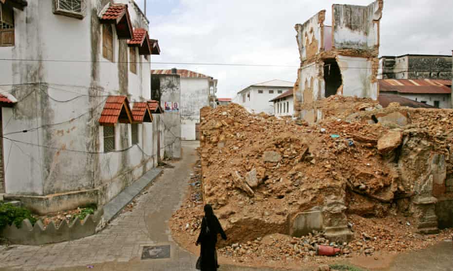 Tough going ... a woman walks past a collapsed building in Zanzibar’s Stone Town.