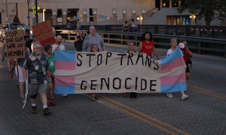Protesters carrying a sign reading ‘Stop trans genocide’ march on the debate arena.