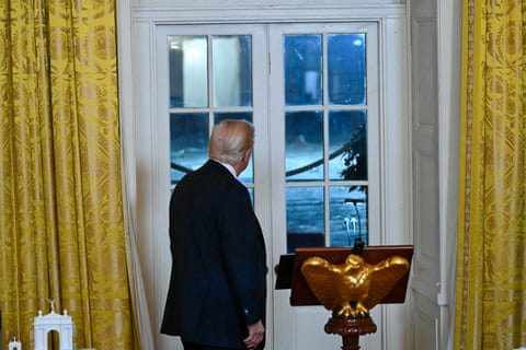 a man in suit looks outside through glass
