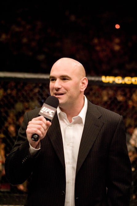 A man holding a microphone pinch crowds blurry beyond him.