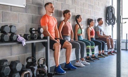 People performing wall sits at a gym.
