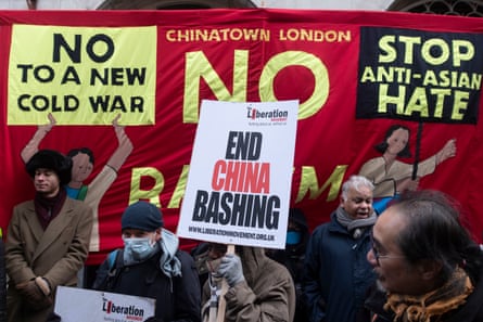 A protester holds a placard reading ‘End China bashing’ against a banner reading ‘No to a new cold war. Stop anti-Asian hate’
