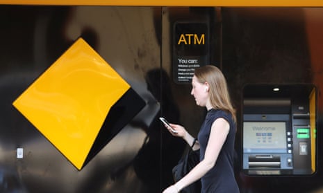 A woman walks past a Commonwealth Bank of Australia logo in Sydney