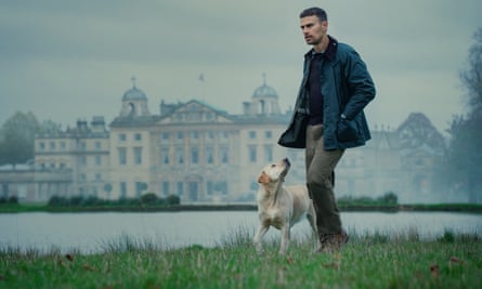 Theo James with a dog by a lake, grand house in the background