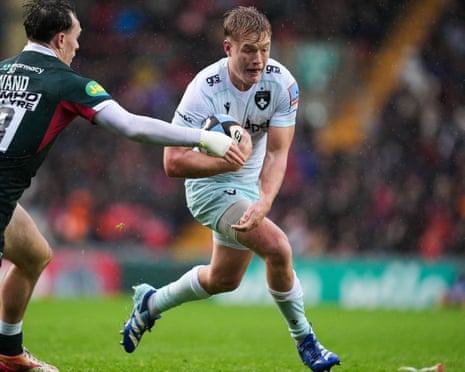 Fin Smith of Northampton Saints carries the ball under pressure from Will Wand of Leicester Tigers