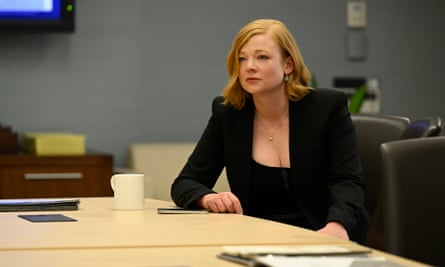 Une femme blanche portant une veste noire est assise à une table.