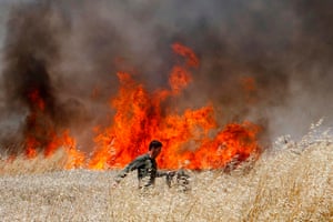 An Israeli soldier battles to extinguish a fire in a wheat field near the kibbutz of Nahal Oz, along the border with the Gaza strip