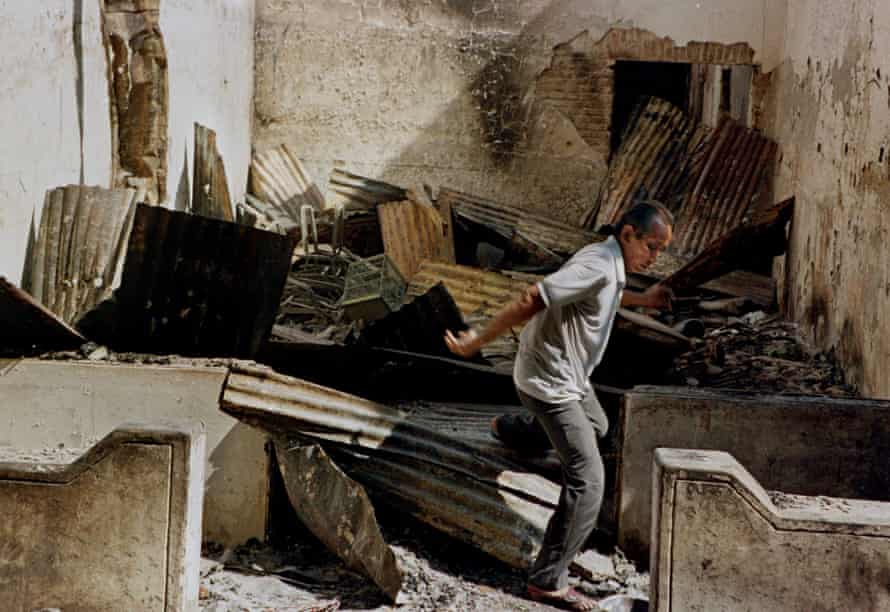An ethnic-Chinese man jumps through the rubble of what remains of his shop after angry mobs ransacked and burned it in Glodok, north Jakarta, Sunday, May 17, 1998.