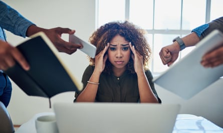 Stock image of a stressed-looking woman holding her hands to her temples as hands thrust objects in front of her including a diary and mobile phone