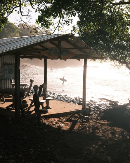 A tin balcony with seats attached to a building which sits on the beachfront.