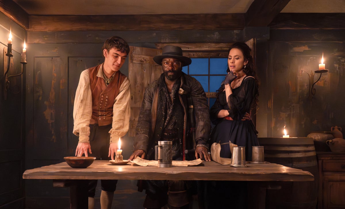 A boy, a pirate and a woman in a candelit ship's cabin