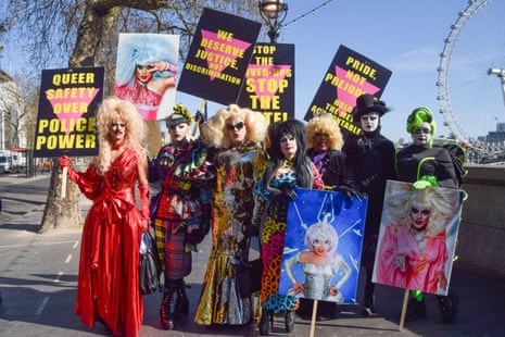 A group of drag queens holding placards, standing outside with the London Eye in the background