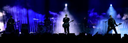 The silhouette of a rock band with a blue lighting show behind them.