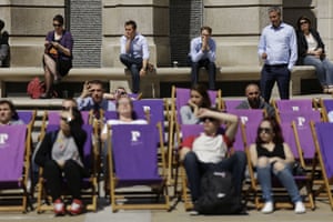 Tourists and workers watch a big screen outside the London Stock Exchange showing Boris Johnson speaking
