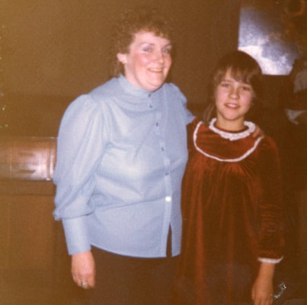 A woman in a blue shirt with her arm round a young girl wearing a velvet brown smock