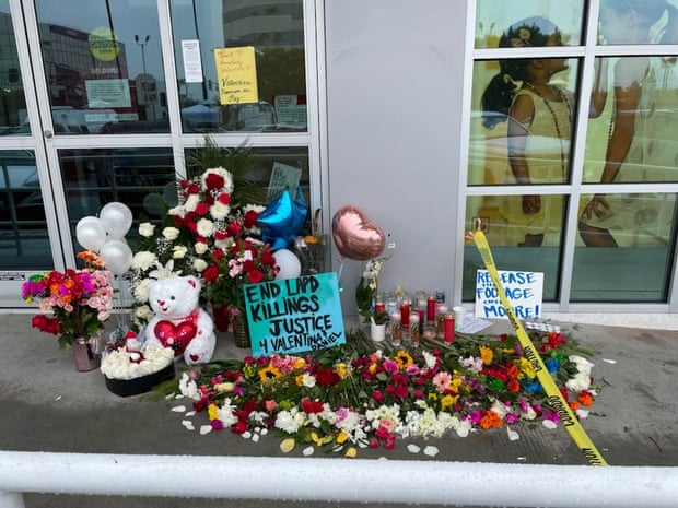Flowers and stuffed animals sit on the concrete outside a building along with a sign that says "End LAPD killings. Justice 4 Valentina & Daniel".