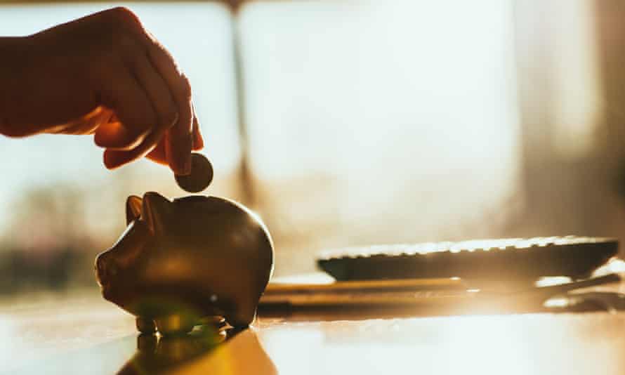 Putting a coin in a gold coloured piggy bank at home.