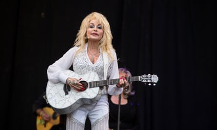 پارتون روي صحنه با كت و شلوار پوشيده شده سفيد و گيتار آكوستيك مشابه